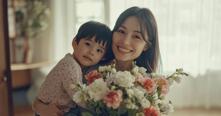A smiling Asian mother cherishes a touching moment with her children, holding flowers and sharing a warm embrace in a cozy home. Heartfelt scene celebrates the bond and love of family on Mother&rsquo;s Day.