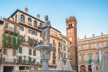 Fototapeta premium Italian square with fountain and Lamberti clock tower and classic architecture with ancient buildings in Verona, Veneto, Italy. Piazza delle Erbe with Fontana di Madonna. Tourist destination