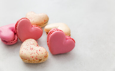 French heart-shaped macarons lying on a plain light background. A perfect image for themes of romance, celebration, and culinary art. Valentine's day, mother's day, congratulations. With love.