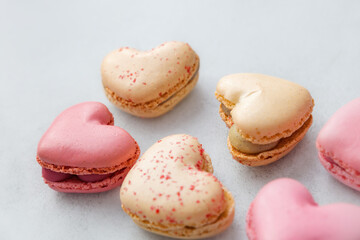 Heart-shaped dessert: refined pastel-colored macarons lying on a smooth plain surface, creating a gentle and elegant mood. Valentine's day, mother's day, congratulations. With love.