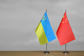 Tabletop flags of Ukraine and China on a gray blurred background