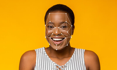 A woman with short hair is smiling while facial recognition technology outlines her features. The...