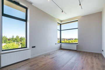 The room is finished, unfurnished. A picturesque summer landscape outside the window.