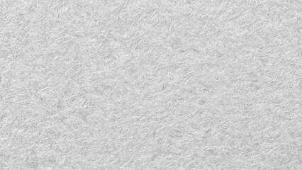 A white wall with a rough texture. The wall is covered in a white paint that has a grainy texture