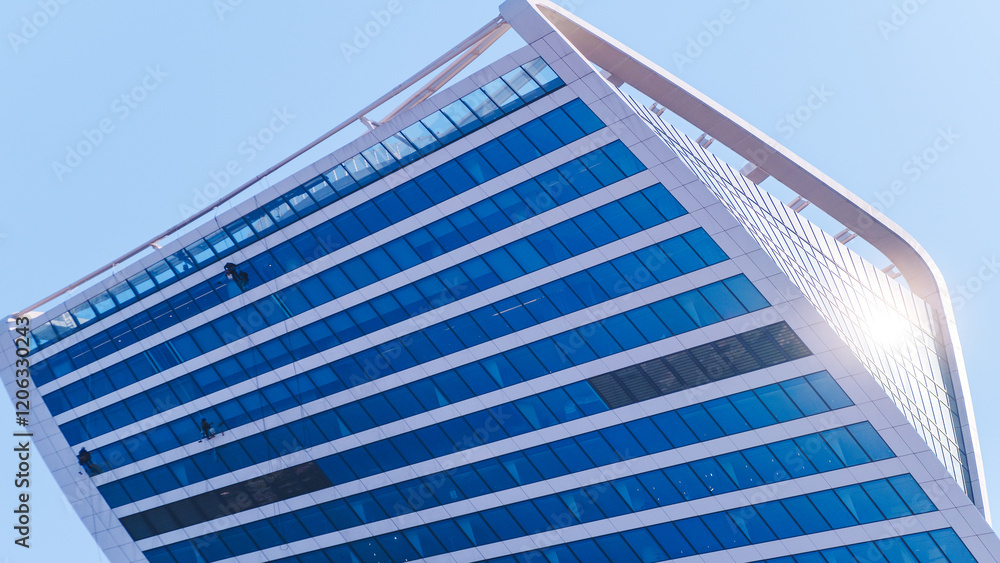 Poster a large, modern building with a blue roof and many windows. the building is very tall and has a uniq