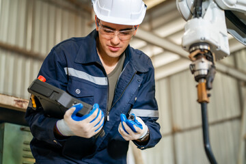 Worker in safety gear operates robotic equipment in manufacturing facility during daytime