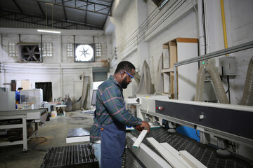 Skilled worker operates machinery in a woodworking workshop during a busy day