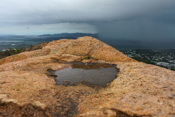 Closeup of a puddle in rocks with a stormy scenic background