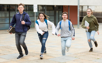 Cheerful teenagers are jogging together on the street and having fun