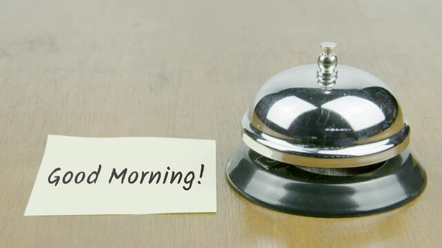 Finger Index Ringing Bell with Good Morning Text or Word on Yellow Note Paper on Desk or Table