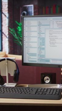 Vertical video Lines of code written on PC workstation screen on development tool application. Debugging software programming language displayed on computer monitor in living room office