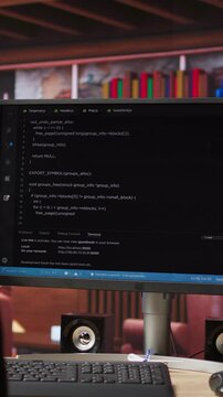 Vertical video Code typed into PC entering commands and running script, panning shot of monitor on desk. Computer display in apartment used for fixing errors in application and implementing features