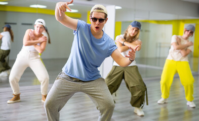 Guy teenager in sunglasses rehearsing modern dances in dance hall