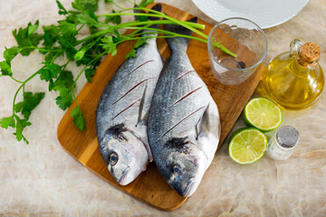 On cutting board are two silver dorado fish, prepared for frying