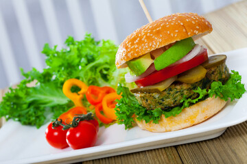 Tasty vegetarian hamburger with soybean cutlet, tomato, avocado and lettuce