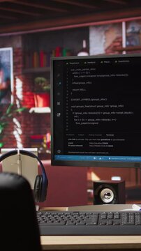 Vertical video Coding interface shown on computer screen on desk in bright home office. Command lines written in code editor program UI on PC display in modern cozy home living room workspace