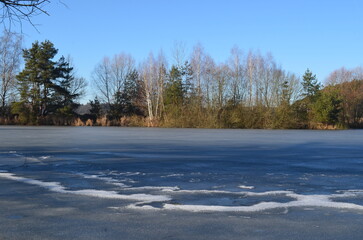 landscape of a winter frozen lake, the surface of the lake is covered with ice, blue sky, sunny day