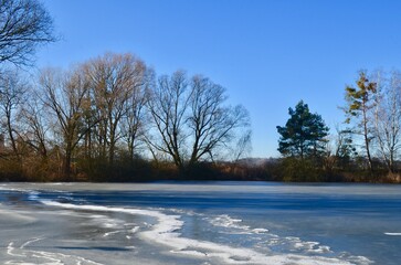 landscape of a winter frozen lake, the surface of the lake is covered with ice, blue sky, sunny day