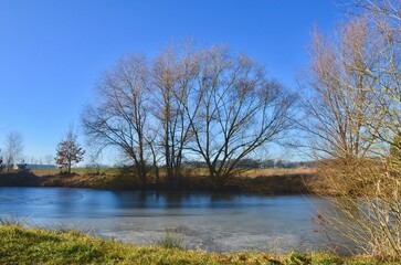 landscape of a winter frozen lake, the surface of the lake is covered with ice, blue sky, sunny day