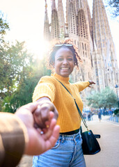 Vertical. POV of young mixed race couple holding hands in front of Sagrada Familia in Barcelona....