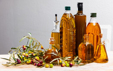 Bottles and carafes with olive oil and fresh olives on wooden table. Ingredients for cooking
