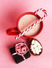 glass of milk with sweets and gift on pink background
