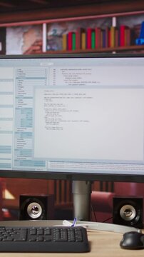 Vertical video Programming code executing software UI on computer monitor in apartment office. Close up of coding application on PC screen used to write and test code in modern apartment, jib down