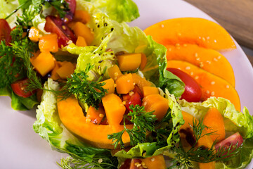 Lettuce, pumpkin, cherry tomatoes, sesame put on a plate. Served with olive oil sauce, salt, pepper, lemon and pumpkin puree..
