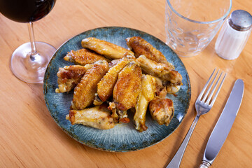 Appetizing fried chicken wings served on dish in restaurant