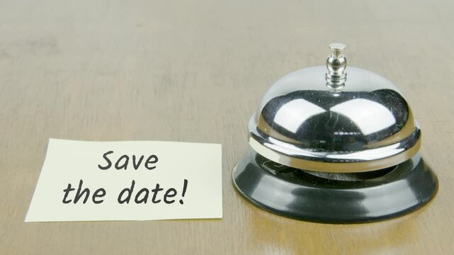 Finger Index Ringing Bell with Save The Date Text or Word on Yellow Note Paper on Desk or Table