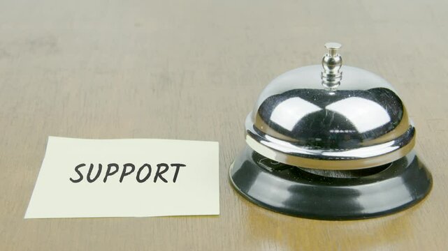 Finger Index Ringing Bell with Support Text or Word on Yellow Note Paper on Desk or Table