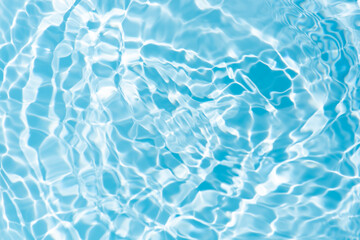 Blue water with ripples on the surface. Defocus blurred transparent blue colored clear calm water surface texture with splashes and bubbles. Water waves with shining pattern texture background.