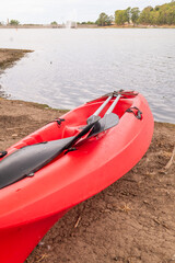 Fototapeta premium A RED KAYAK ON THE SHORES OF A LAGOON ON A CLOUDY DAY