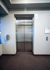 Closed silver elevator doors in a modern interior setting