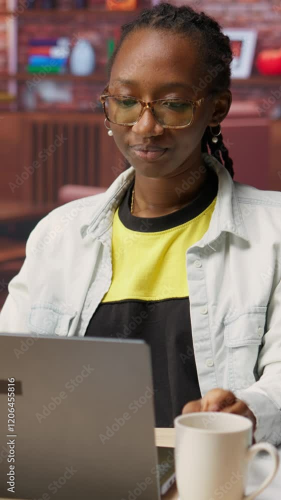 Poster vertical video student at home drinking coffee and browsing internet on notebook, researching inform