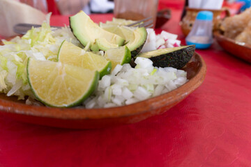 Plato con limones, rábanos y aguacate en plato de barro, comida mexicana