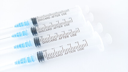 disposable medical syringes of different sizes, blue in color. neatly arranged on a white background