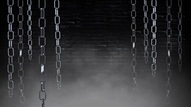 Swinging Chains in the Dark 4K Loop features metallic chains hanging down and swinging in a dark room with a brick wall in back and smoke rising in a loop.