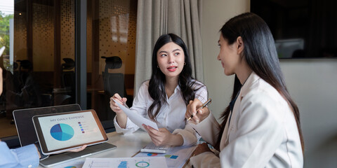 Focused women discussing daily expense analysis during a collaborative business meeting with digital tablet