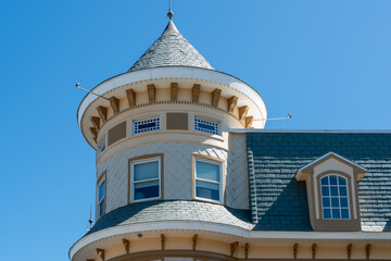 The roof of a historic Victorian-style roof with an antique turret. The adjoined roof is gabled...