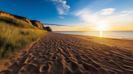 A sandy path marked by footprints, illuminated by the golden hour light, leading toward a calm sea...