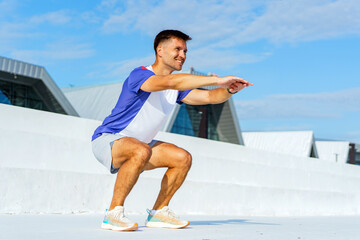 Fitness enthusiast performs squats outdoors with modern architecture in the background on a clear...
