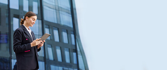 Business professional engages with digital tablet outside modern urban office building during...