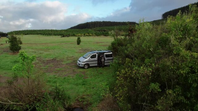 van parked on grass with two people leaning in Whakamaru's scenic Waikato, New Zealand