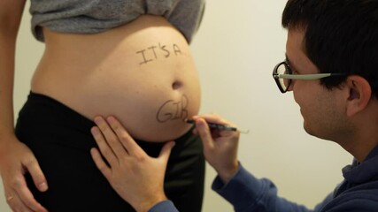 Happy father writes It is a Girl on the belly of his pregnant wife to reveal the gender of the future baby