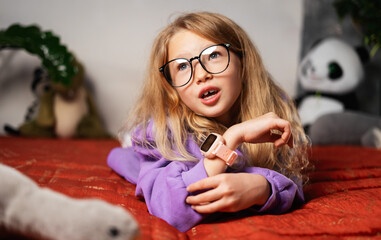 Child wearing smartwatch explores balance between play and learning. Wearable gadget offers mobile...