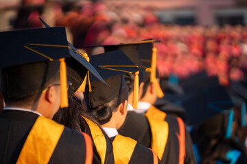 A group of graduates stand in a row, wearing black and yellow graduation caps and gowns. Concept of accomplishment and pride as the graduates celebrate their achievements