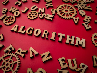 Closeup wooden word and wooden gear with the word ALGROITHM on a red background