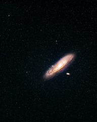 A view of the Andromeda Galaxy photographed with a 135mm lens. The barred spiral Andromeda Galaxy is shining bright along with its two satellite galaxies and some nearby stars.