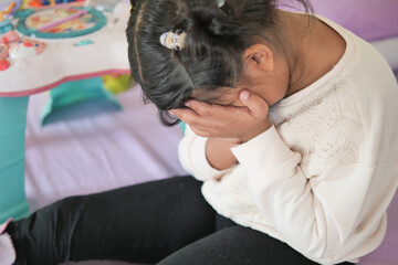 a upset child girl cover her face with hand 